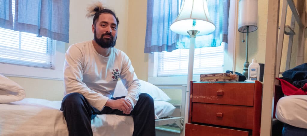 Will sits on a bed in his room at a transition home operated by San Antionio AIDS Foundation.